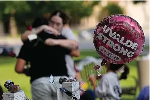  ?? (AP Photo/eric Gay) ?? Visitors hug as they place flowers at a memorial Wednesday in Uvalde, Texas. One year ago a gunman killed 19 children and two teachers inside a fourth-grade classroom at Robb Elementary School in Uvalde.