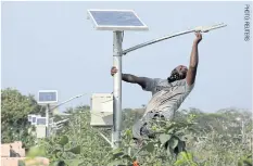  ??  ?? A worker installs a solar-powered lamp in a public park in Chennai, India.