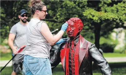  ?? JAMES JACKSON WATERLOO REGION RECORD ?? Volunteer Laura Herner scrubs the red paint off the statue of Sir John A. Macdonald in Baden Sunday morning.