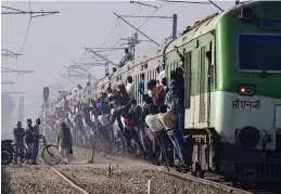  ?? — AFP ?? Passengers hang onto a train as it departs from a station on the outskirts of New Delhi on Tuesday.