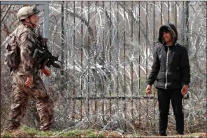  ?? (AP/Darko Bandic) ?? A migrant holds stones Saturday as a Turkish special police officer patrols in Pazarkule, Turkey, along the border with Greece.