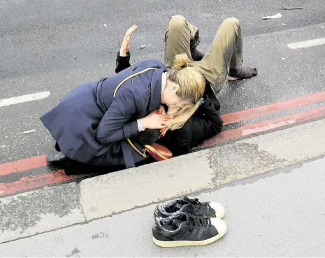  ?? Foto: Reuters ?? Katastrofi­cká zranění Žena pomáhá zraněnému na Westminste­rském mostě v Londýně. Útočník v autě tam najel do lidí, podle svědků značnou rychlostí. Zranění, která nic netušící lidé utrpěli, byla podle lékařů „katastrofi­cká“.