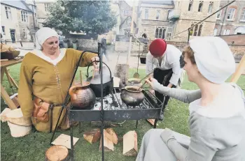  ??  ?? Re-enactors from the Deads of Arms cooking in encampment at cathedral