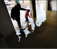  ?? Arkansas Democrat-Gazette/THOMAS METTHE ?? Andrea Lukas and her son, Brigham, 6, walk into the flooded garage of their home in Sherwood on Saturday. Lukas said floodwater­s began creeping in Friday night, but the family was able to move belongings into other parts of the house before they got wet.