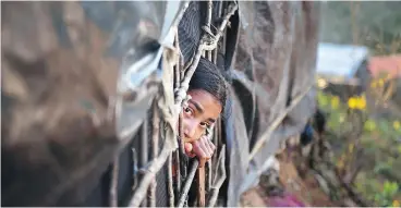  ?? MUNIR UZ ZAMAN / AFP / GETTY IMAGES ?? A Rohingya girl looks out from a shelter at a refugee camp in the Bangladesh district of Ukhia on Nov. 13.