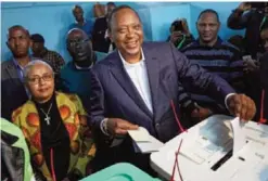  ??  ?? NAIROBI: Kenya’s President Uhuru Kenyatta casts his vote, accompanie­d by his wife Margaret (center-left) in Gatundu, north of Nairobi yesterday.—AP