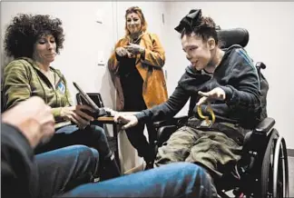  ?? ERIN HOOLEY/CHICAGO TRIBUNE ?? With her parents, Matt and Megan Lassman, at left, 14-year-old Penelope Lassman, right, who has cerebral palsy, uses her iPad during a visit with cannabis specialist Farah Zala, center, at Innovative Wellness on Nov. 11.