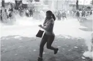  ?? TOMADO DEL CARABOBEñO ?? Una mujer corre frente al Comando de la Policía.