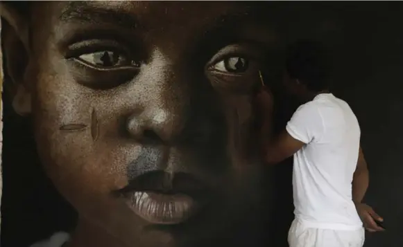  ?? SUNDAY ALAMBA/THE ASSOCIATED PRESS ?? Babajide Olatunji puts a finishing touch on one of his works at his studio in Ile-Ife, Nigeria. His charcoal renderings of faces with tribal markings sell for thousands of dollars.