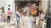  ??  ?? Employees at the Sohna factory try to douse the fire on Thursday