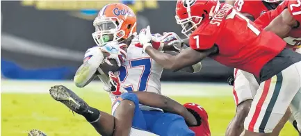  ?? JOHNRAOUX/AP ?? Florida running backDameon Pierce is stopped byGeorgia’s Monty Rice, lower left, andTyrique Stevenson on Saturday.