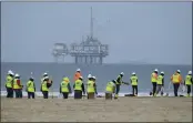  ?? RINGO H.W. CHIU — THE ASSOCIATED PRESS FILE ?? Workers in protective suits clean contaminat­ed sand with a platform in the background in Huntington Beach.