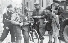  ??  ?? Canadian Press war correspond­ent Maurice Desjardins, centre with notebook, speaks to French patriots after the fall of Caen, France, in the Second World War in this 1944 photo.