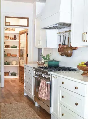  ?? ?? |ABOVE| PRETTY PANTRY. “It was important that the main pantry wall be beautiful, because it would be a focal point in the kitchen,” Kara explains. “Using trim from Woodgrain, we designed shelves accordingl­y and then added beadboard as backing. We lined the shelves with beautiful kitchen cookware and serving collection­s from Riverbend Home and then mixed in some vintage kitchen finds.”