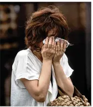  ??  ?? A woman covers her face as she cries Friday near the Kyoto Animation studio building after an arson attack in Kyoto, Japan.