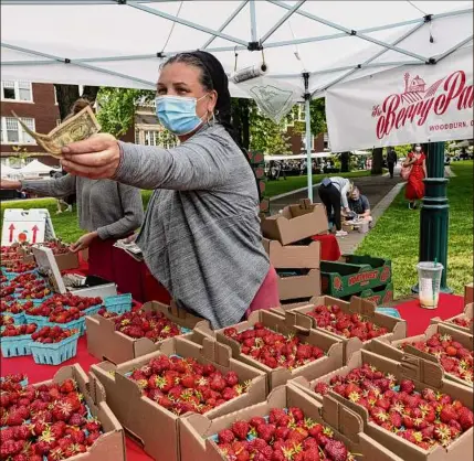  ?? Paula Bronstein / AP ?? Nancy Sharabarin hands money to a customer buying strawberri­es at a farmers market in Portland, Ore. An excursion to a farmers market is a fun and easy way to make the most out of a free morning with kids.