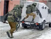  ?? — PTI, AP ?? Security personnel ( above) take positions while family members of paramilita­ry personnel are evacuated during a gunbattle with militants near a CRPF camp in Srinagar on Monday.