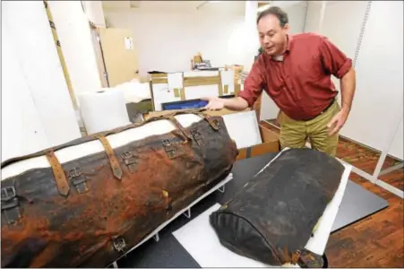  ?? PETE BANNAN — DIGITAL FIRST MEDIA ?? R. Scott Stephenson, vice president of collection­s at the Museum of the American Revolution, looks at George Washington’s portmantea­u, a suitcase used during the Revolution­ary War. It is printed with “Height Dorchester 1775” and “Battle of Yorktown 1781” from the Revolution.