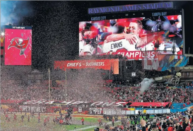  ??  ?? Las pantallas del Raymond James Stadium proyectan la imagen del abrazo de Tom con su compañero Evans después del triunfo de los Buccaneers.