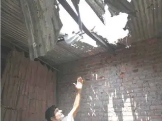  ??  ?? RANBIR SINGH PURA: An Indian villager shows a roof damaged in alleged firing from the Pakistan side into a residentia­l area at Abdullian village. — AP