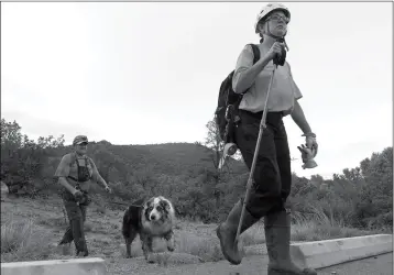  ??  ?? MEMBERS OF THE TONTO RIM SEARCH AND RESCUE TEAM exit a section of forest after searching along the banks of the East Verde River for victims of a flash flood Sunday in Payson. Search and rescue crews, including 40 people on foot and others in a...