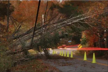  ?? ROBERT F. BUKATY — THE ASSOCIATED PRESS ?? A car leaves a trail of light as it passes under power lines weighed down by toppled trees in Freeport, Maine, Tuesday. Utility crews scrambled to restore power throughout New England on Tuesday, one day after a severe storm packing hurricane-force...