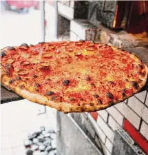  ?? Lisa Nichols/ For Hearst Connecticu­t Media ?? Hot pizza coming out of the oven at Sally's Apizza in New Haven on June 13.