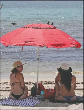  ?? (AP/Lynne Sladky) ?? People sit on Hollywood Beach during the new coronaviru­s pandemic in Hollywood, Fla. In hard-hit South Florida, beaches from Palm Beach to Key West will be shut down for the Fourth of July holiday weekend.