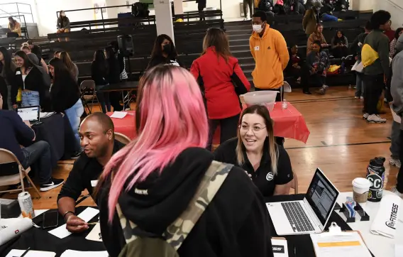  ?? Helen H. Richardson, The Denver Post ?? Tyler Wortham, general manager of 24 Hour Fitness in Aurora, left, and Megan Bartlett, general manager of 24 Hour Fitness at Colorado and Alameda, right, talk with students during a job fair on Tuesday in Denver.