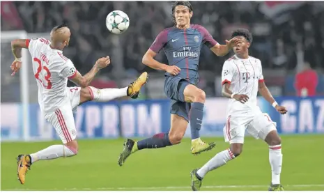  ??  ?? Die Bayern-profis Arturo Vidal (l.) und David Alaba (r.) bemühen sich um den Ball. Der lachende Dritte jedoch war Edinson Cavani von Paris St. Germain. Er erzielte den Treffer zum 2:0 für die Franzosen. Foto: afp