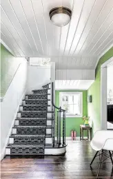  ??  ?? Apple-green grasscloth wallpaper and a black-and-white geometric carpet runner on the stairs make an inviting foyer space.