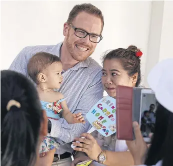  ??  ?? CENTRE OF ATTENTION: Gordon Lake and baby Carmen pose for pictures with Thai supporters outside court last year. Mr Lake says his daughter loves smiling for the camera.