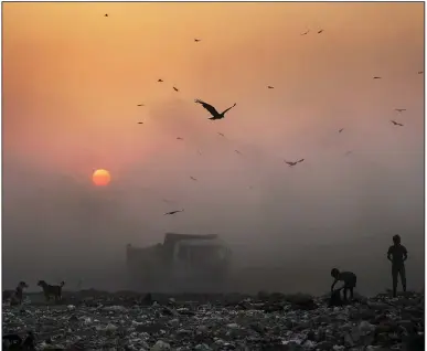  ?? (AP/Altaf Qadri) ?? A thick blanket of smoke envelops young ragpickers searching for reusable material at a garbage dump in New Delhi, India.