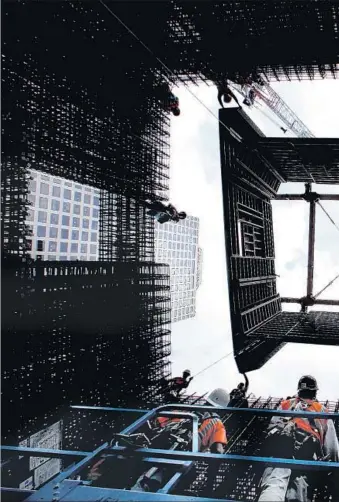  ??  ?? CONSTRUCTI­ON WORKERS guide a jumping wall form system into place as it is lowered into posi-