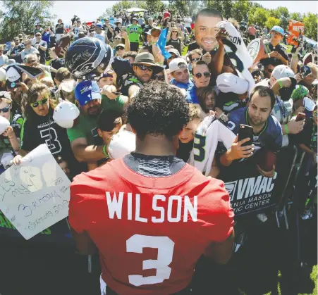  ?? THE ASSOCIATED PRESS FILES ?? Seahawks QB Russell Wilson signs autographs at training camp last July. Less than a year later, the NFL is facing losses in the tens of billions if the season is cancelled. It could take years for profession­al sports to rebound from the economic damage wrought by COVID-19.