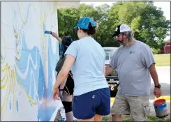  ?? (NWA Democrat-Gazette/Annette Beard) ?? Jones adds his touch to the mural as Fanning and Abbot work on the blues of the sea.