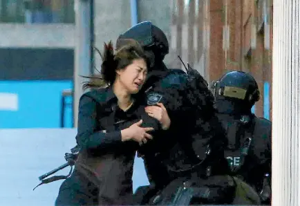 ?? PHOTOS: REUTERS ?? A hostage is grabbed by a police officer after escaping the Lindt cafe in central Sydney. After a group of hostages fled, gunman Man Haron Monis killed cafe manager Tori Johnson, forcing police to move in.