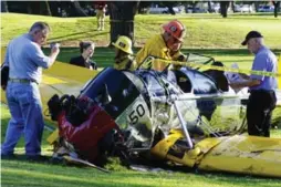  ?? DAMIAN DOVARGANES/THE ASSOCIATED PRESS ?? Officials examine Harrison Ford’s vintage airplane on the Penmar Golf Course.