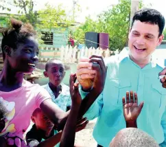  ??  ?? Jamaica Public Service CEO Emanuel DaRosa hands candy to children in Majesty Gardens yesterday while on a walkthroug­h marking a regularisa­tion milestone in the community and the end of the USAID Ready Board Project.