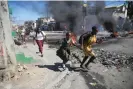  ?? Odelyn Joseph/AP ?? A mother and daughter run past a roadblock during police protests in Portau-Prince, Haiti, late January. Photograph: