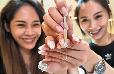  ?? — CHAN boon Kai/the Star ?? Off with the colouring: Tang (right) helping eve Kung, 36, remove nail polish from her fingers as she looks forward to cast her vote tomorrow.