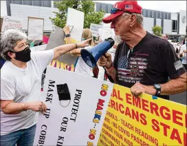  ?? AJC FILE ?? People on both sides of the mask issue protest before a recent Cobb school board meeting as mask debates continue to heat up.