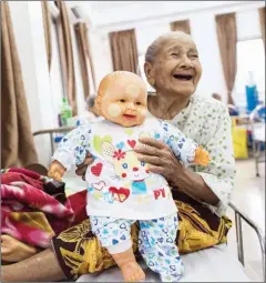  ?? YE AUNG THU/AFP ?? An elderly resident of the Twilight Villa nursing home smiles as she shows a doll which she keeps as close company at the centre on July 4.