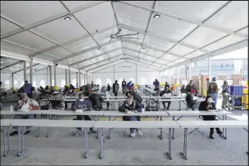  ??  ?? With the indoor dining hall closed because of the COVID-19 pandemic, clients eat Thursday under a tent outdoors at Catholic Charities of Southern Nevada.