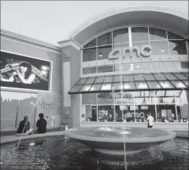  ?? Frederic J. Brown AFP/Getty Images ?? A COUPLE watch a screen outside an AMC theater in Monterey Park in 2012. In Los Angeles, MoviePass has dropped its service at AMC Century City 15.