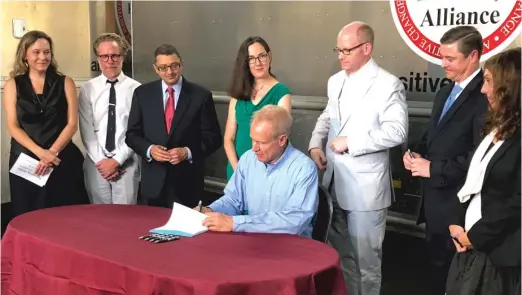  ?? LISA MANN/FOR THE SUN-TIMES ?? Gov. Bruce Rauner signs the Alternativ­es to Opioids Act on Tuesday at the Chicago Recovery Alliance.