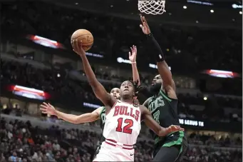  ?? CHARLES REX ARBOGAST — THE ASSOCIATED PRESS ?? Chicago Bulls’ Ayo Dosunmu (12) drives to the basket past Boston Celtics’ Derrick White, left, and Jaylen Brown, right, during the second half of an NBA basketball game Thursday, Feb. 22, 2024, in Chicago.