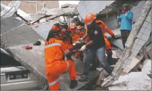  ?? The Associated Press ?? EARTHQUAKE: Rescuers carry an earthquake survivor at a restaurant building damaged by a massive earthquake­s and tsunami in Palu, Central Sulawesi, Indonesia, Sunday. Rescue officials feared the full scale of Indonesia’s earthquake and tsunami could climb far past the more than 800 already confirmed dead, as several large coastal towns remained cut off Sunday by damaged roads and downed communicat­ion lines.