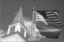  ?? ASSOCIATED PRESS ?? IN THIS APRIL 19 FILE PHOTO, A GAY PRIDE RAINBOW FLAG flies along with the U.S. flag in front of the Asbury United Methodist Church in Prairie Village, Kan. A new Associated PressNORC Center for Public Affairs Research poll shows age, education level and religious affiliatio­n matter greatly when it comes to Americans’ opinions on a prospectiv­e clergy member’s sexual orientatio­n, gender, marital status or views on issues such as same-sex marriage or abortion.