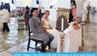  ??  ?? HAGONOY, Philippine­s: Photo shows the bride Jobel Delos Angeles, 24, and her groom during their wedding amidst a flooded church in Hagonoy town, Bulacan town, north of Manila. — AFP